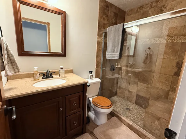 Tile-surround shower with a glass enclosure, pebble-finish shower floor, and built-in shelving