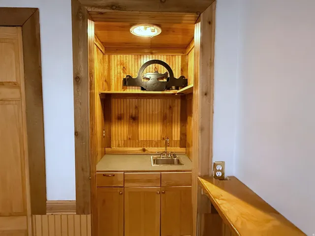 Built-in niche with wood paneling, recessed lighting, integrated sink with faucet, base cabinetry, and a countertop