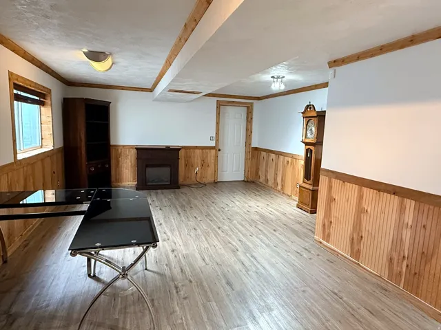 Wood-finish flooring, half-wall wood paneling, and an electric fireplace