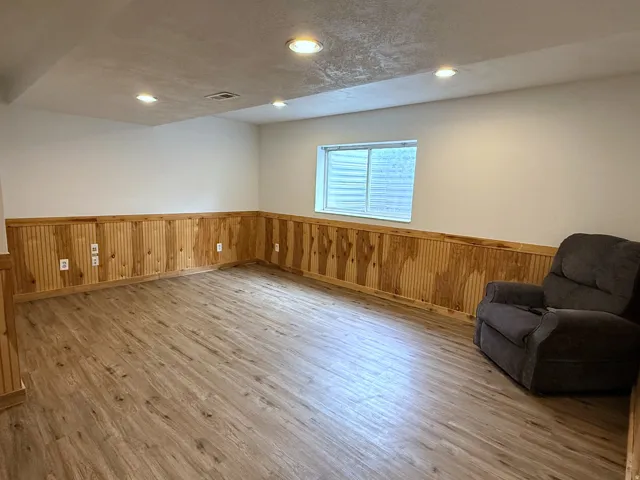 Recessed lighting, wood-finish flooring, wood paneling, and a large window
