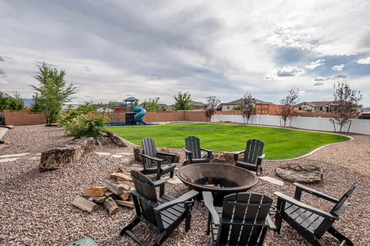 Expansive backyard featuring a central fire pit area, a large grassy area, and a built-in play structure