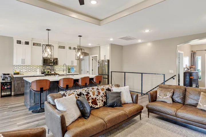 Open-concept living space with wood-finish flooring, recessed lighting, and a tray ceiling