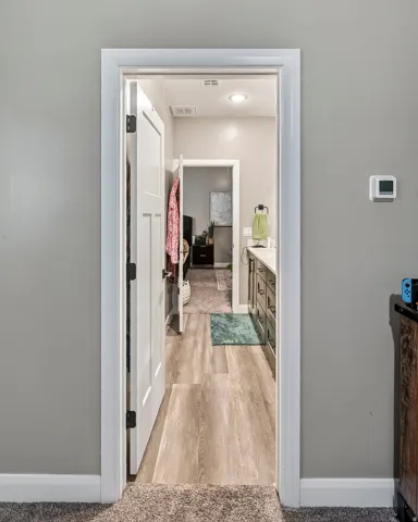 Wood-finish flooring leading to a vanity with integrated sink and cabinetry