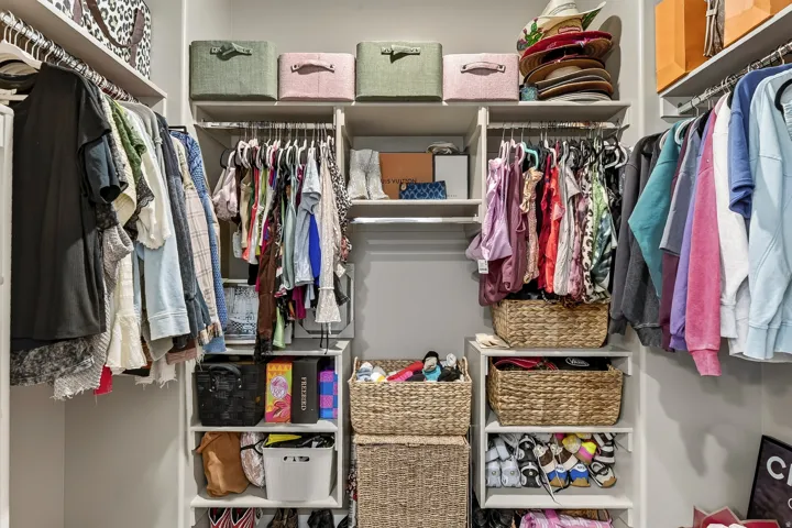 Built-in closet organization system featuring multiple hanging rods, shelving units, and integrated storage cubbies