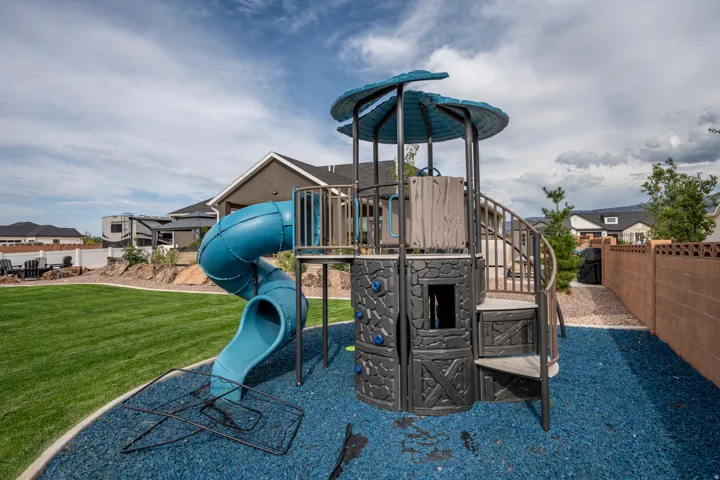 Expansive backyard oasis featuring a multi-level play structure with integrated spiral slide, elevated platform tower with protective canopy roof, and durable blue safety surfacing
