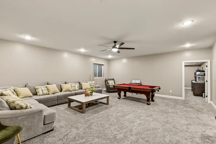 Expansive recreation room featuring neutral carpet flooring, recessed lighting, and a ceiling fan