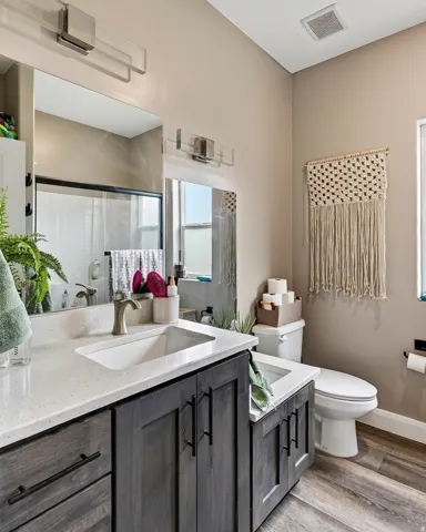 Spa-inspired primary bathroom featuring a dual-sink vanity with dark cabinetry, white quartz countertops, and brushed nickel fixtures
