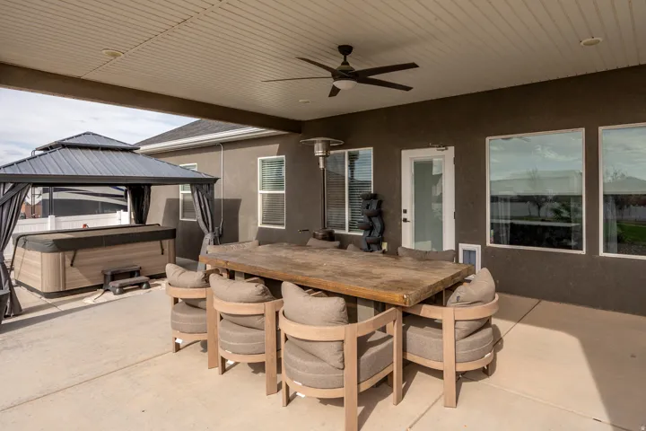 Covered patio with a ceiling fan, a smooth concrete surface, and stucco exterior walls