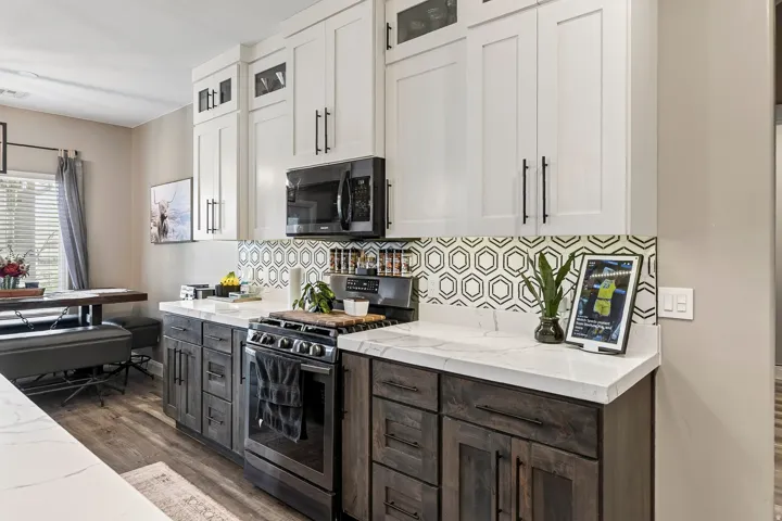 Modern kitchen featuring white upper cabinetry, dark wood-finish lower cabinetry, white countertops, and a geometric tile backsplash
