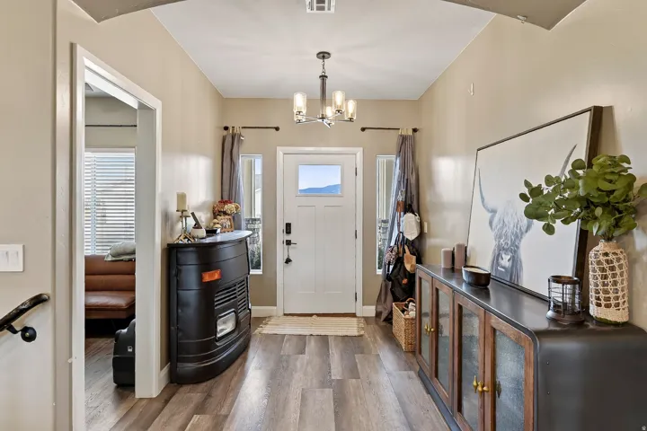 Wood-finish flooring, white paneled door with glass insert, and a contemporary chandelier