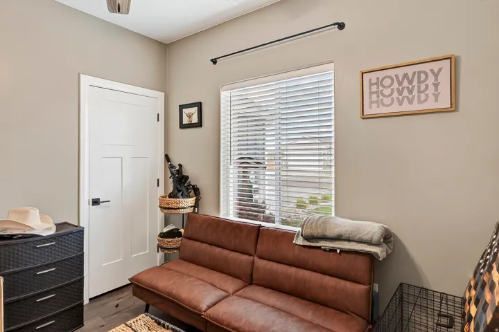 Neutral wall paint, window with blinds, overhead ceiling fan, and a white interior door with black hardware