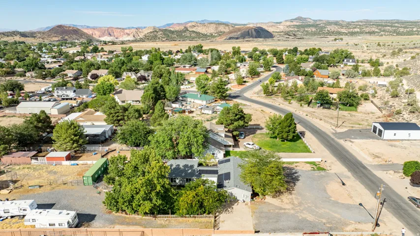 Residential area with varied housing styles and mature trees, surrounded by arid landscape and distant mountains