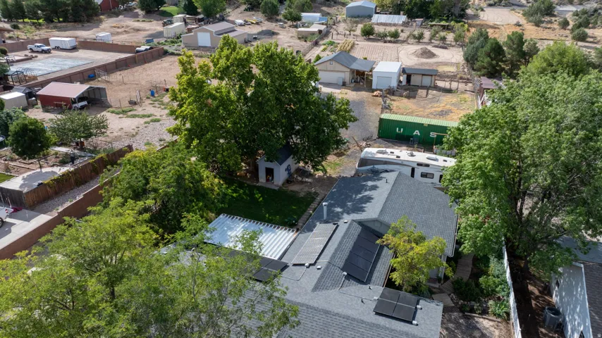 Modern residence featuring a contemporary paved patio with integrated seating areas, mature shade trees providing natural screening, and a streamlined architectural footprint