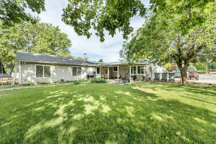 Expansive green lawn, mature trees, and a stucco exterior