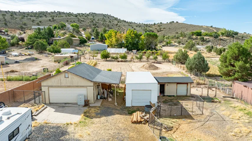 Spacious rural property featuring multiple outbuildings including detached garages with overhead doors, metal storage structures, and wooden fencing