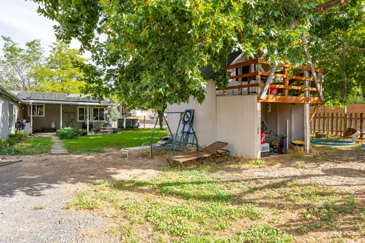 Spacious backyard retreat featuring mature tree coverage, detached storage structures, and established landscaping