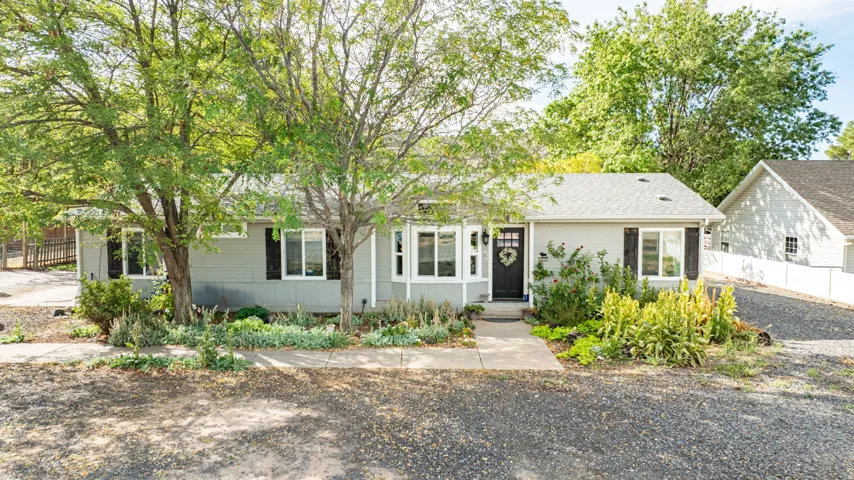 Single-story residence featuring light gray siding, white trim, and a dark entry door