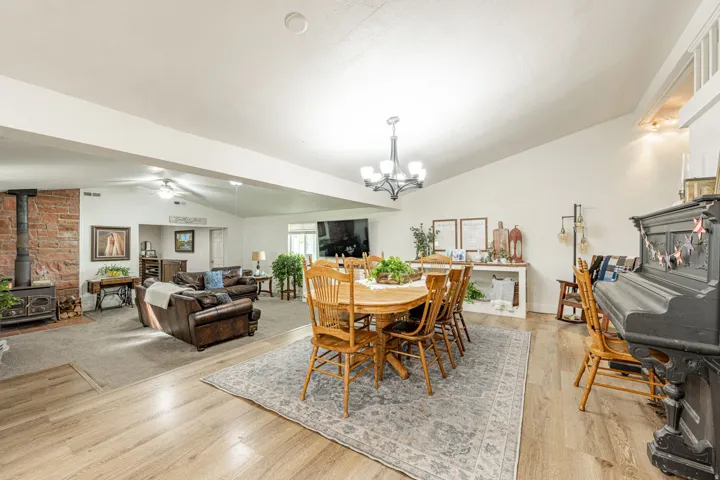 Vaulted ceilings, wood-finish flooring, exposed brick chimney, ceiling fan, and chandelier