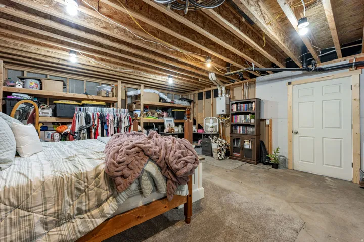 Unfinished basement featuring exposed wood joists, a panel door, and concrete flooring
