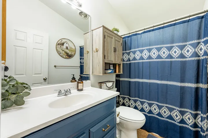 Spa-inspired bathroom featuring a dual-sink vanity with white quartz countertop, navy cabinetry with brass hardware, and polished chrome faucetry