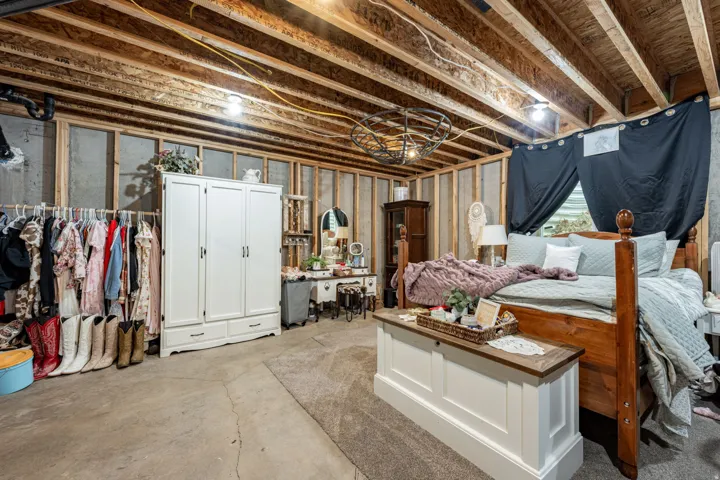 Spacious primary bedroom featuring exposed beam ceiling, wood-post bed frame, and built-in cabinetry