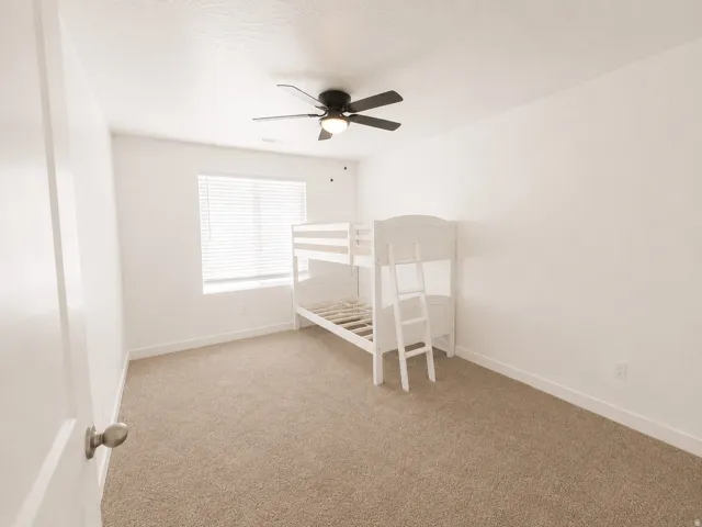 Neutral-toned carpeting, white walls, and a window with blinds