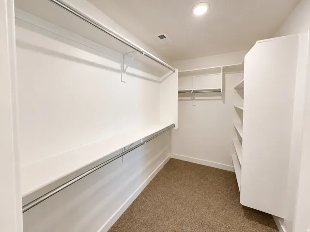 Walk-in closet featuring extensive built-in shelving, multiple hanging rods, and recessed lighting