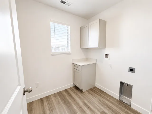 Light wood-finish flooring, built-in cabinetry with a countertop, and a window with blinds