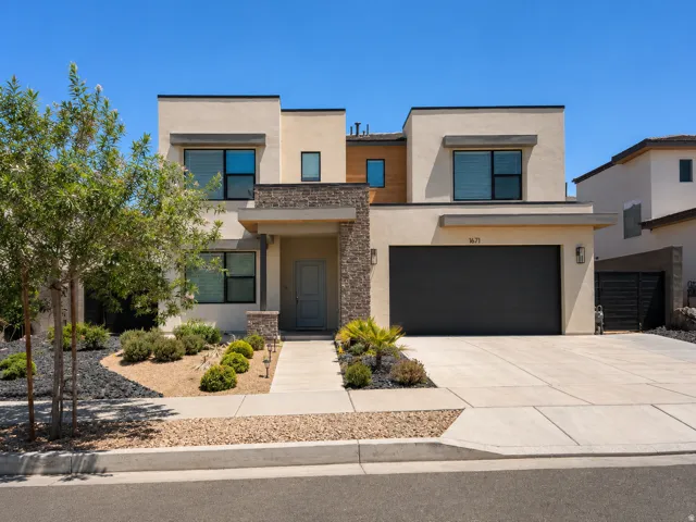 Modern exterior with a light stucco finish, stone accents, and a dark garage door