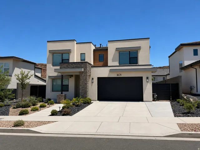 Contemporary exterior featuring a flat roofline, stone veneer accents, and a dark garage door