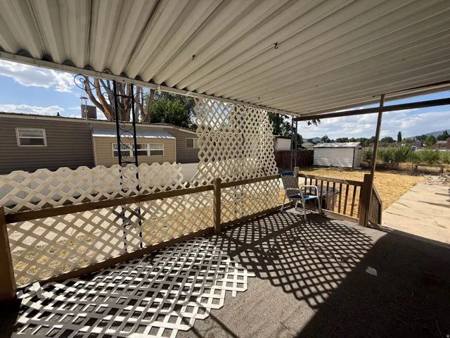 Covered outdoor patio with lattice railing, an exterior storage shed, and a concrete pathway