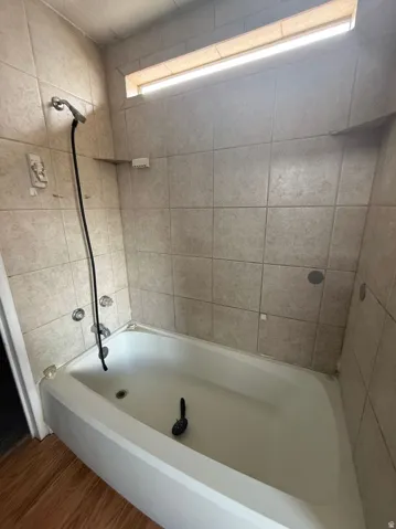Bathtub with a tiled surround and a handheld shower fixture