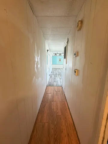 Wood-finish flooring extending through a corridor with paneled walls
