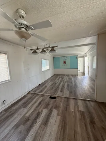 Wood-finish flooring throughout, white paneled wall accents, and an overhead ceiling fan
