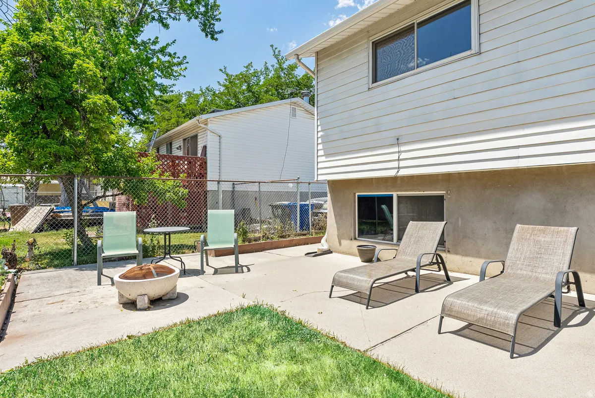 Concrete patio featuring a fire pit and a grassy area