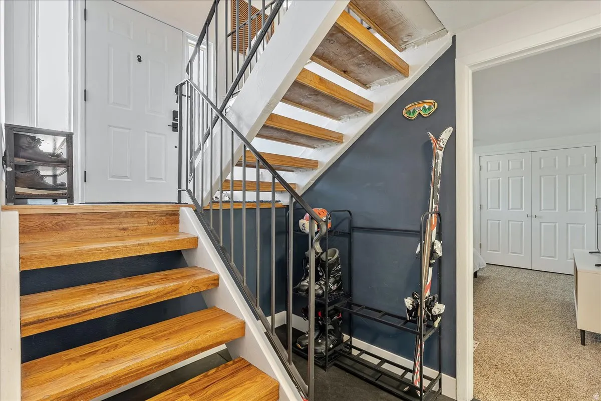 Hardwood treads with a modern metal railing, a paneled entry door, and bi-fold closet doors