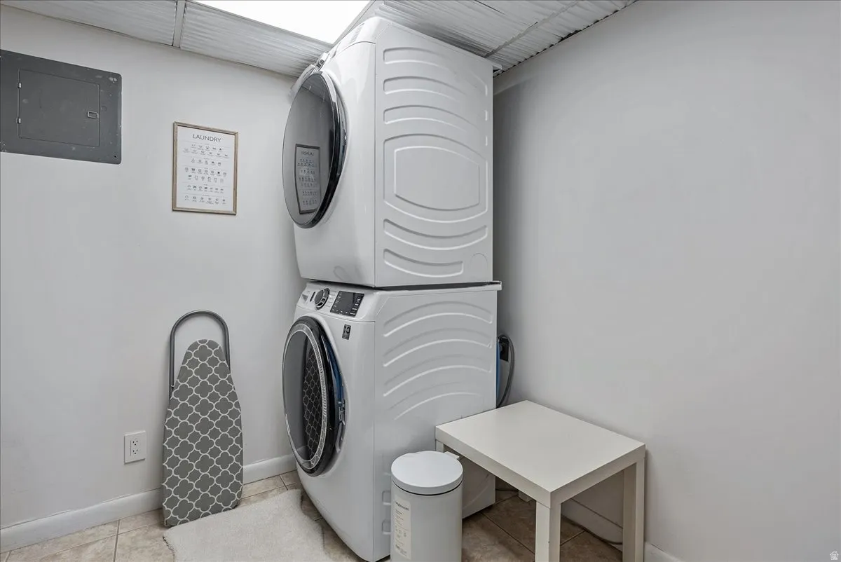 Stackable washer and dryer, white walls, and tile flooring