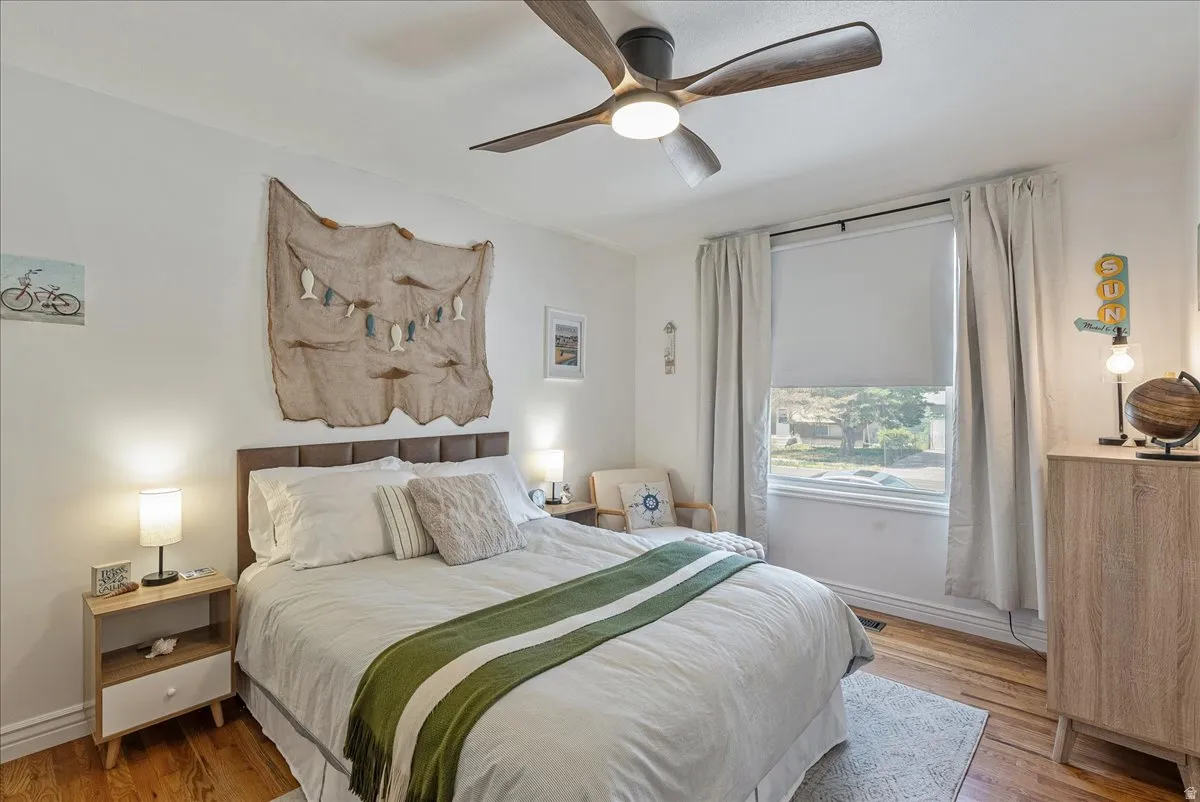 Wood-finish flooring with a ceiling fan and overhead lighting
