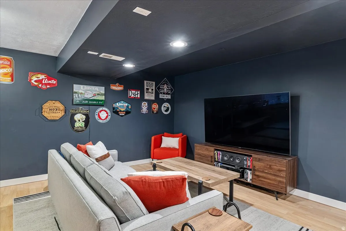 Recessed lighting illuminates this space featuring light wood-finish flooring and a dark accent wall