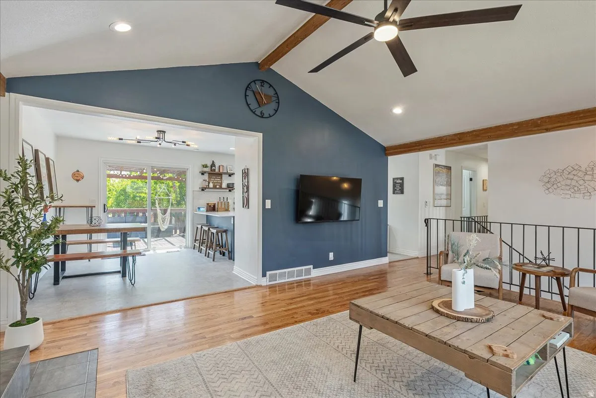 Vaulted ceilings with exposed wood beams, wood-finish flooring, recessed lighting, and a contemporary ceiling fan