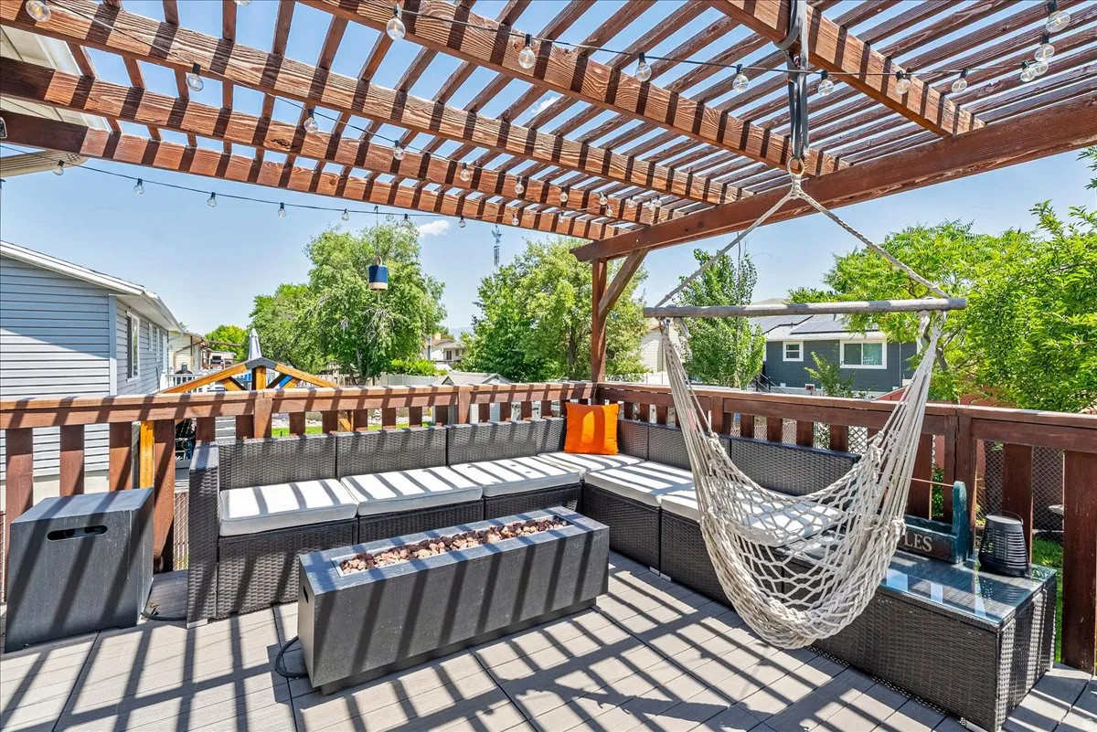 Wood pergola with string lighting, composite deck flooring, and wood railing