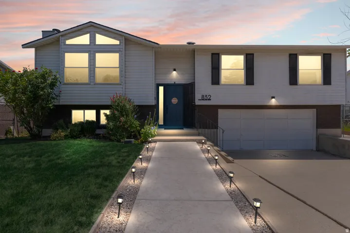 White siding exterior with a dark blue entry door, an attached two-car garage, and a concrete driveway