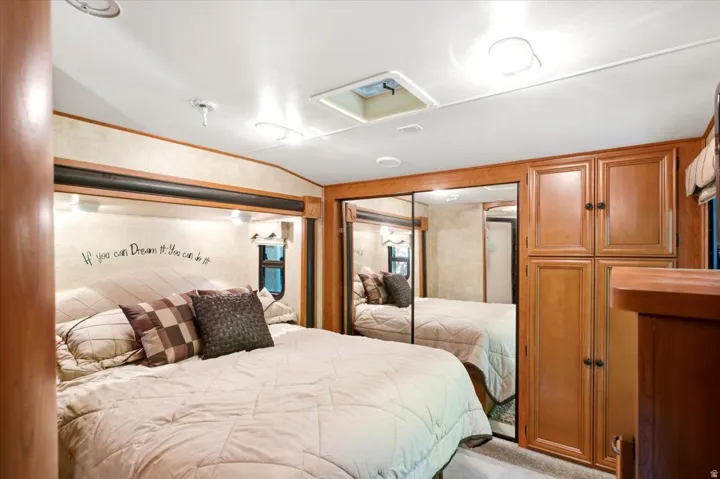 Built-in cabinetry with wood-finish doors, mirrored closet doors, recessed ceiling lighting, and overhead bed lighting