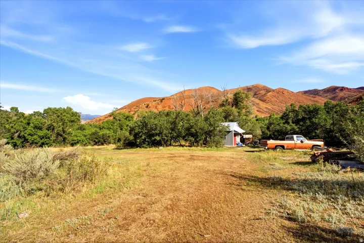 Expansive undeveloped land with a small red shed and a natural, unpaved terrain