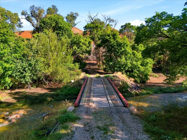Wooden bridge spanning a natural stream, surrounded by mature trees and natural vegetation