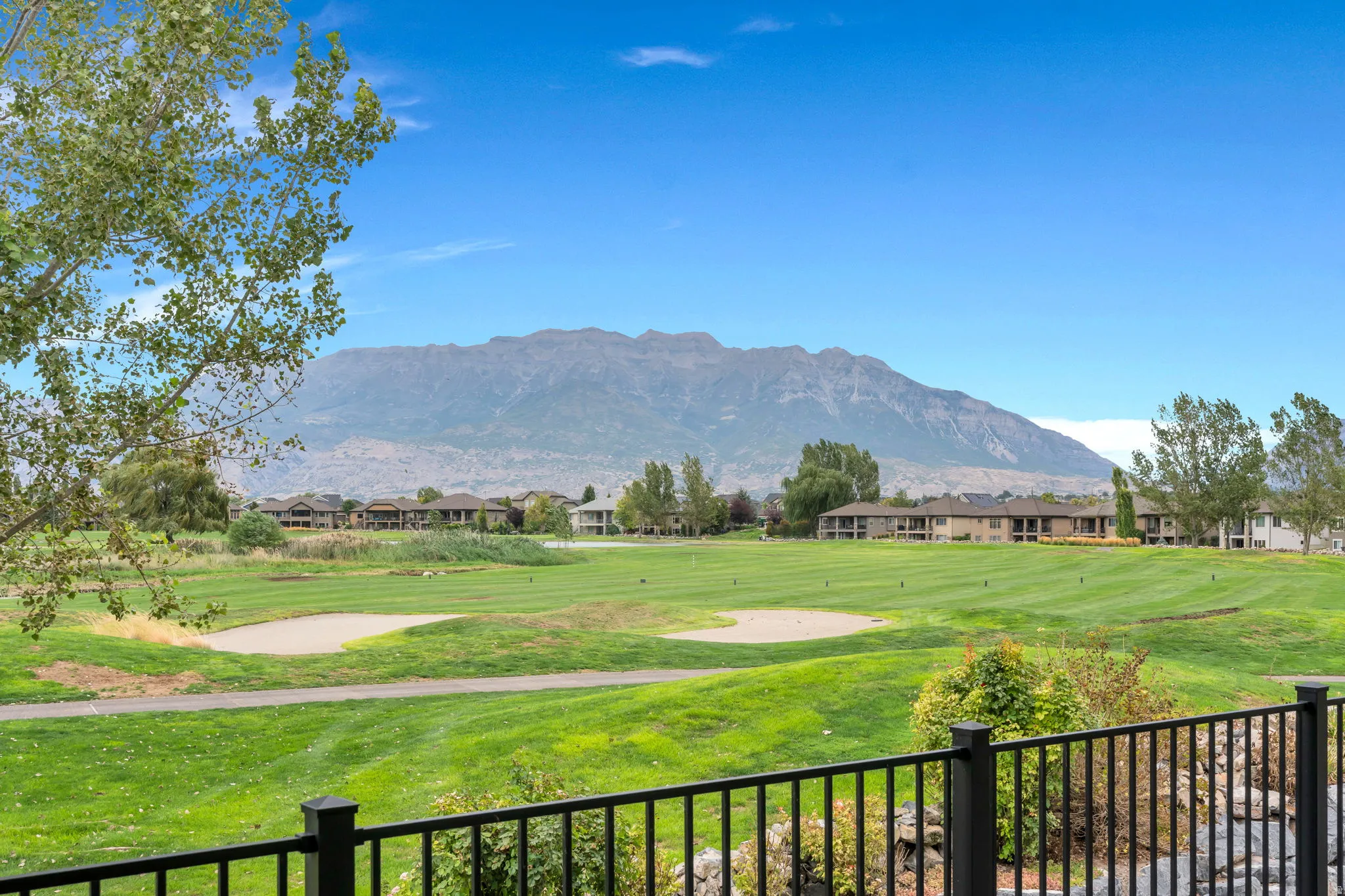 Mountain backdrop, golf course, manicured greens, sand traps, and residential structures