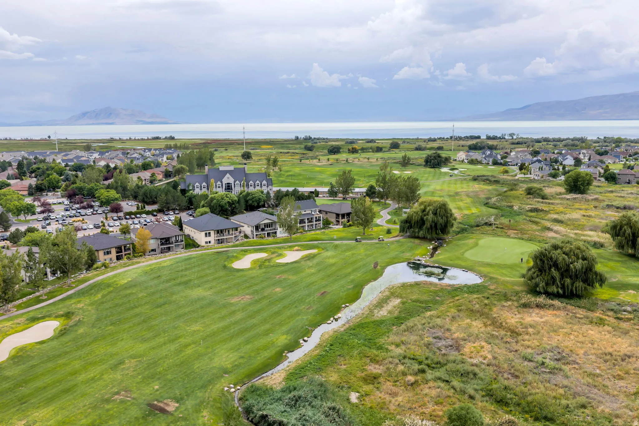 Expansive golf course setting featuring manicured greens and a water feature