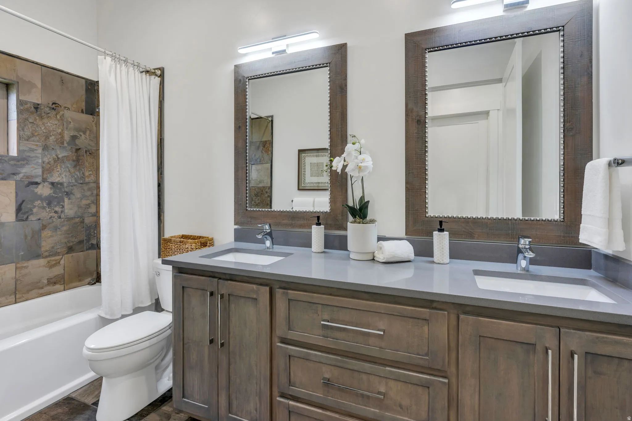 Dual vanity with integrated sinks, light gray countertop, and distressed wood-finish cabinetry
