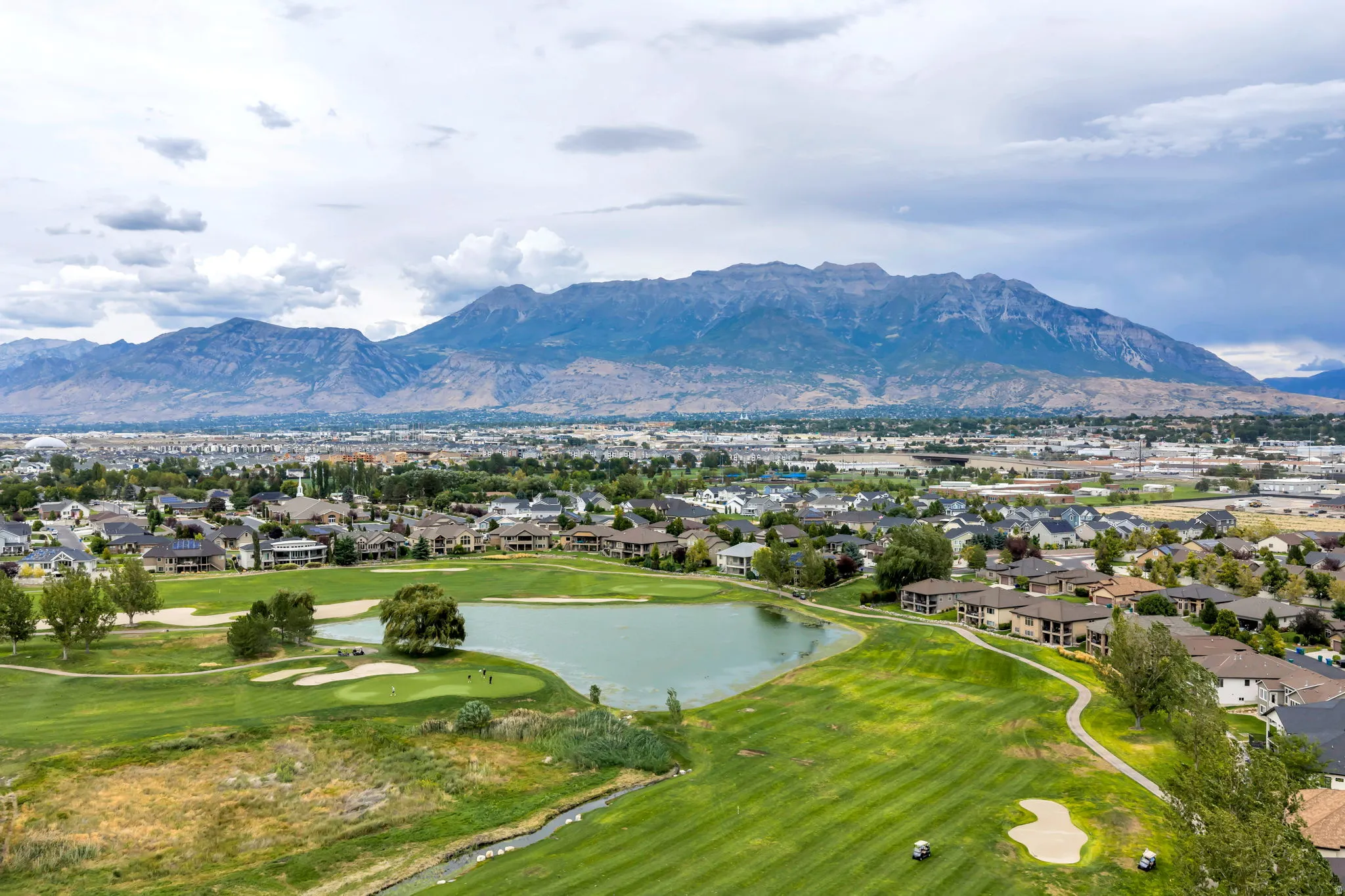 Expansive golf course setting featuring manicured greens and a water hazard