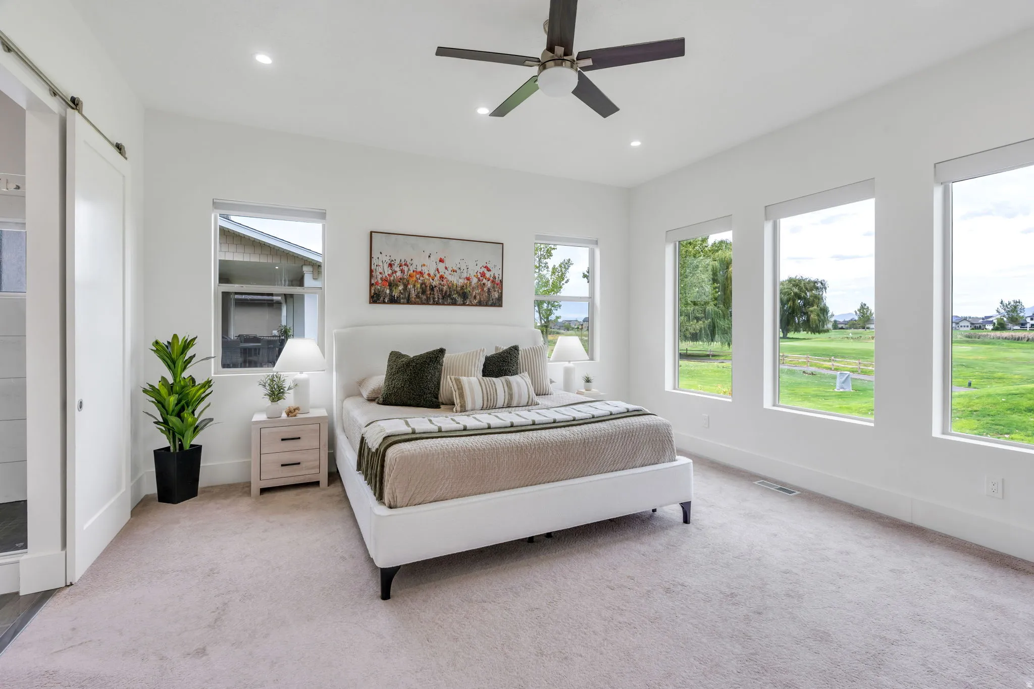 Recessed lighting, ceiling fan, multiple windows, carpet flooring, and barn door entry